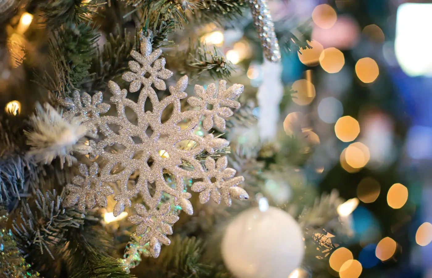 Gros plan sur une décoration de sapin de Noël avec une étoile scintillante et des lumières floues en arrière-plan, créant une ambiance festive et élégante.